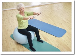 Senior woman sitting on ball and exercising with dumbbells