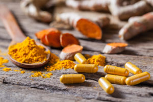Turmeric powder, turmeric capsule and turmeric capsules on wooden background