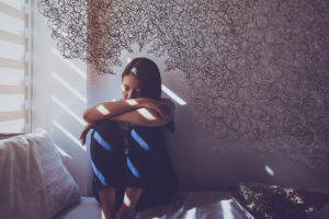 anxiety idea: woman sitting in dark room with squiggly drawings coming in towards her head