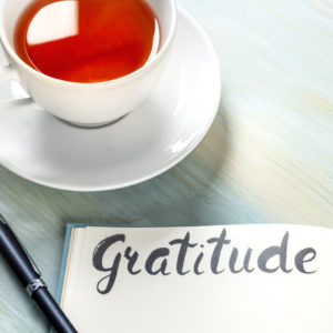 Gratitude journal with a pen and a cup of tea.