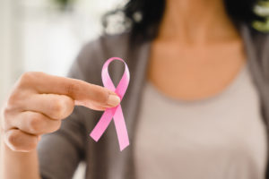 Cropped photo of woman holding pink ribbon for fighting against breast cancer, supporting women 