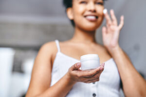 Shot of a woman applying lotion to her face