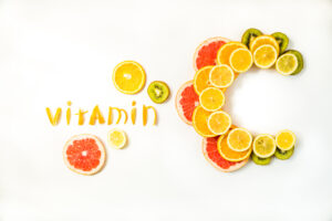 Vitamin C letters made of citrus fruits - lemon, grapefruit, orange and kiwi slices on white background