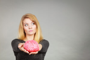 Woman thinking or confused and holding fake brain out in front of her hands