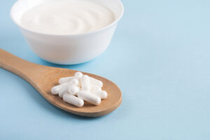 Homemade yogurt with probiotics and capsules pills on a wooden spoon. 