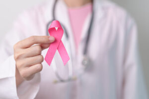 Pink ribbon held in foreground, by doctor in background