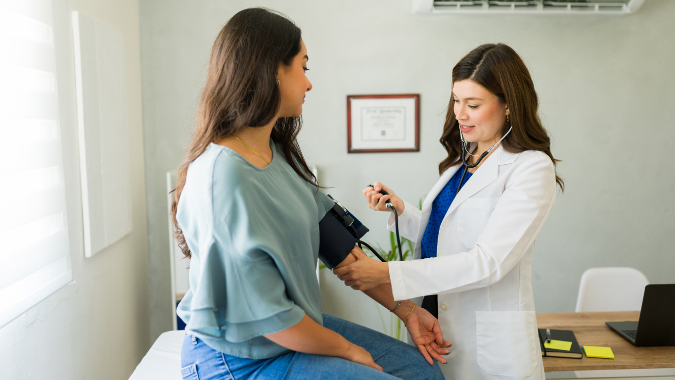 Doctor is measuring the blood pressure of a young adult female patient in a medical consultation